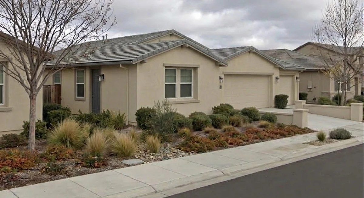 A single-story stucco home in a Southern California tract with a front yard of drought-tolerant grasses, succulents and gravel in place of lawn