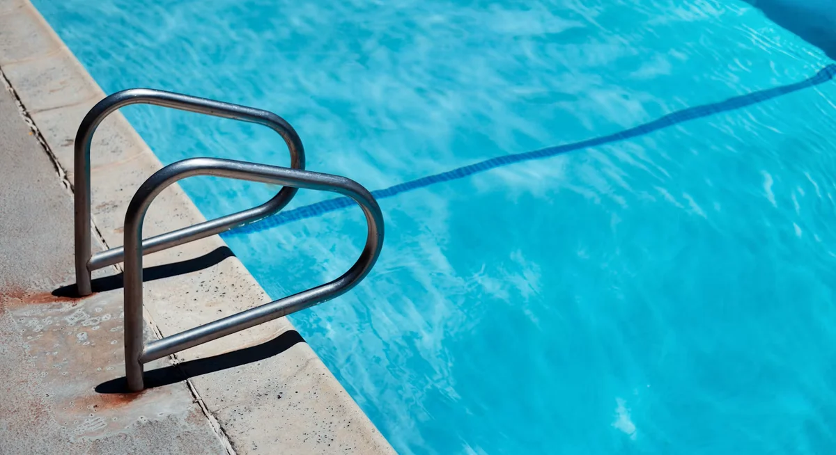 A pool technician testing water chemistry at the edge of a backyard pool